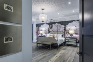 Bedroom with 4 poster bed, floral wallpaper and crystal light fitting.
